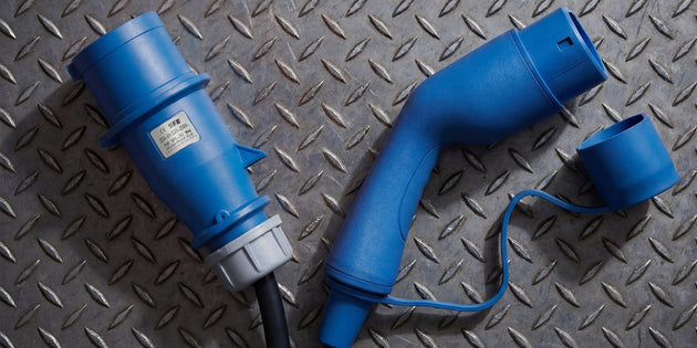 Three phase blue CEE plug beside a Type 2 charging connector on metal