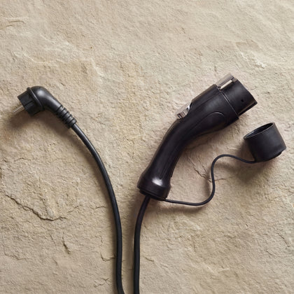 Type 1 connector and Schuko plug of the Voldt® Portable Charger on a beige surface