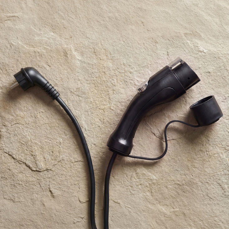 Type 1 connector and Schuko plug of the Voldt® Portable Charger on a beige surface